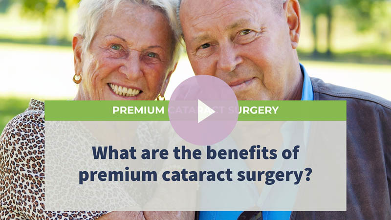 A senior couple walking in the park, smiling and looking at the camera.