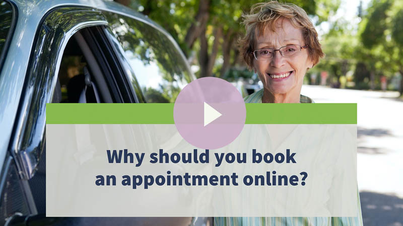 Senior woman with glasses standing next to her car on the side of the road.