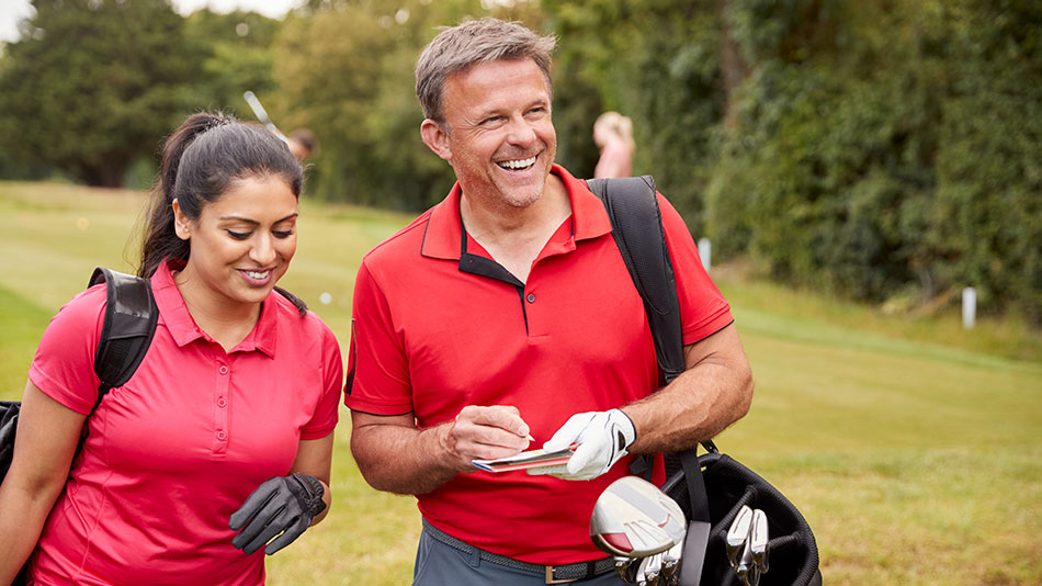 Middle-aged man wearing a red shirt, noting down his score while playing golf.